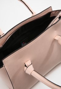 Borsa tote in pelle beige con rifiniture nere, dotata di scomparto principale con zipper e doppie tracolle. L'interno ha una texture liscia.