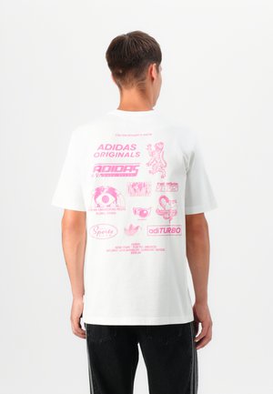White cotton t-shirt featuring pink graphic prints on the back, including logos and text, with short sleeves and a relaxed fit.
