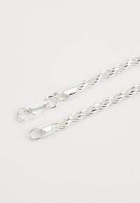 Collana in argento con catena intrecciata e chiusure a moschettone. Superficie liscia e riflettente; design intrecciato e elaborato; struttura leggera e flessibile.