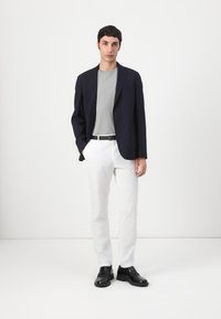 Tengerész kék blézer, szürke póló, fehér nadrág és fekete cipő; sima anyag, testre szabott fazon, minimalista design, látható minták vagy díszítések nélkül.