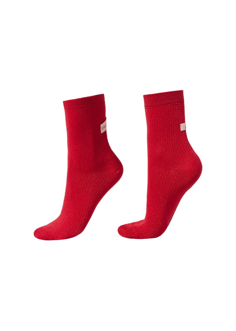 Chaussettes rouges côtelées de hauteur moyenne, avec une texture douce et une petite étiquette sur le côté. Tissu lisse et élastique assurant un confort optimal.