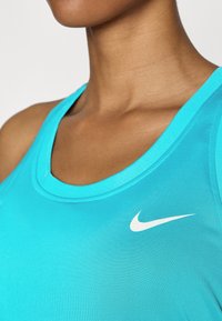 Turkis atletisk tanktop lavet af glat stof, med en rund halsudskæring og et hvidt Nike-logo på venstre side.