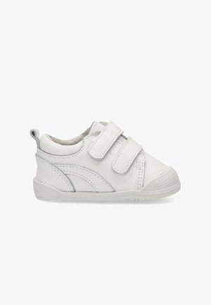 Zapatilla blanca de cuero con correas de velcro, punta redondeada, suela texturizada y un diseño de acento curvado en gris claro.