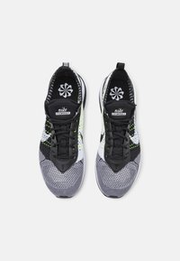 Nike Flyknit sneakers med en svart, vit och neongrön mönstrad ovandel, som har en texturerad yta och svarta snören.