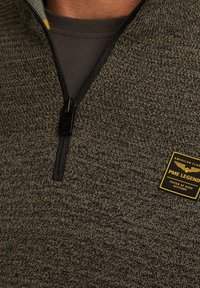 Donkergroene, gestructureerde ritssluitingtrui met een zwarte ritssluiting en een PME Legend logo patch in het geel. Heeft een hoge hals en een contrasterende laag eronder.