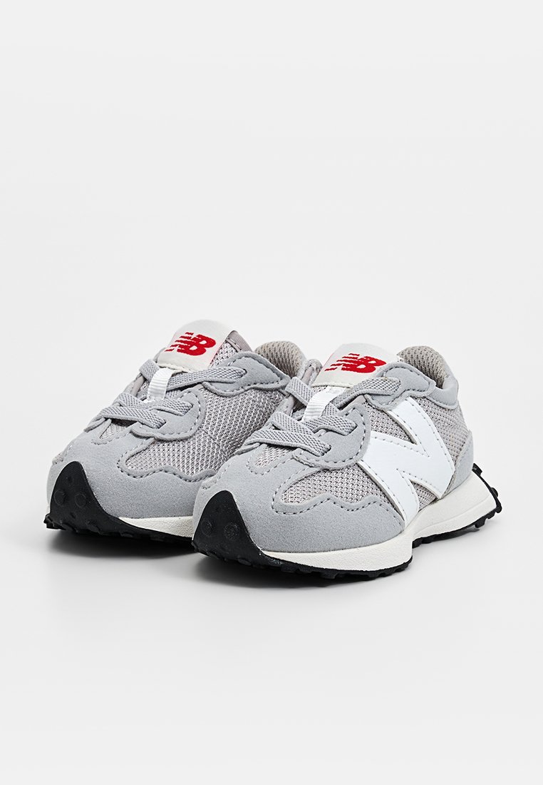 Baskets de sport grises en maille et daim, avec des accents blancs, des semelles en caoutchouc noir et des formes arrondies. Logo rouge sur la languette.