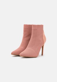 Stivaletti rosa alla caviglia con tomaia in maglia texturizzata, punta appuntita e dettagli in suede, caratterizzati da un alto tacco a spillo e un colletto rigato.