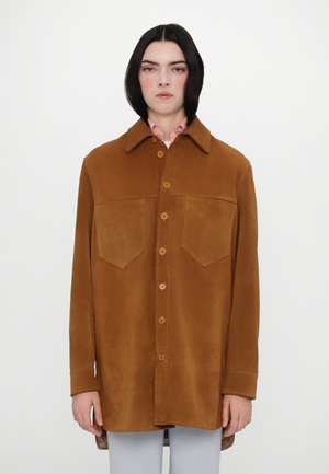 Braune Wildleder-Übershirt mit zwei Brusttaschen und Knopfverschluss. Verfügt über einen spitzen Kragen und dezente Stickdetails an den Taschen.