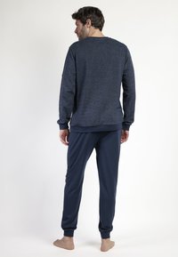 Conjunto de lounge azul marino que incluye una camiseta de manga larga texturizada y pantalones ajustados con puños elásticos, fabricado en una tela suave y transpirable.