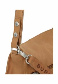 Angolo di una borsa a tracolla in pelle color tan con superficie texturizzata, hardware in argento, una tracolla rimovibile con bottoni incisi e dettagli con zip.