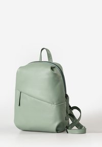 Mintgrüner Leder-Rucksack mit glatter Oberfläche, runder Form, vorderem Reißverschlussfach und verstellbaren Trägern. Minimalistisches Design.