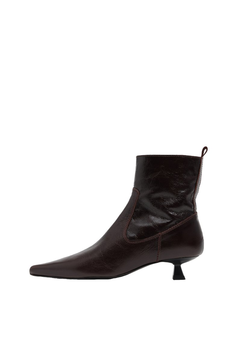 Botín de cuero marrón oscuro con punta afilada, tacón bajo tipo kitten y tirador en la parte trasera, mostrado desde el lado exterior.