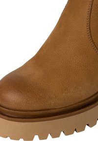 Bottine en cuir marron avec une finition lisse, bout rond et semelle en caoutchouc chunky beige avec une surface texturée et un profil de bande de roulement prononcé.