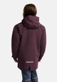 Veste imperméable bordeaux avec capuche, comportant une ventilation arrière, des accents réfléchissants et des manches longues. Texture lisse et coupe décontractée.