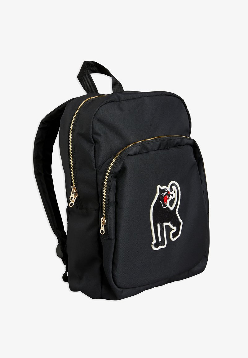 Mochila de nylon preta com zíperes dourados, com um gato preto bordado no bolso frontal. Alças ajustáveis para os ombros.