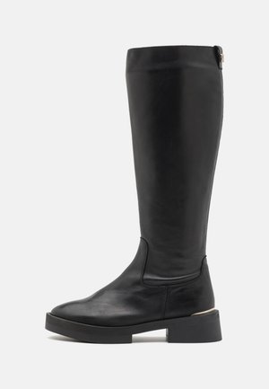 Botte en cuir noir jusqu'aux genoux avec une texture lisse, un bout rond, un talon carré et un accent métallique subtil à l'arrière supérieur.