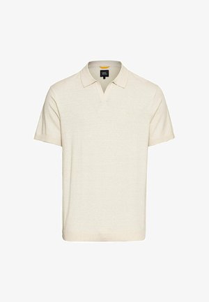 Beige Polo-Shirt mit kurzen Ärmeln aus weichem Stoff, mit V-Ausschnitt, geripptem Kragen und dezentem Logo auf der linken Brust.