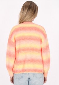 Pastellfärgad gradienttröja med rosa, orange och gula ränder. Mjuk textur, lös passform och ribbat avslut vid ärmar och nederkant.