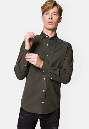 Oliwkowa, zapinana na guziki koszula z kołnierzykiem, długimi rękawami i kieszonką na piersi. Wykonana z miękkiego materiału o gładkiej teksturze i białymi guzikami.