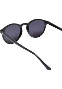Occhiali da sole neri rotondi con lenti scure, montatura in plastica liscia e aste sottili. Presentano un design minimalista senza marchi visibili.