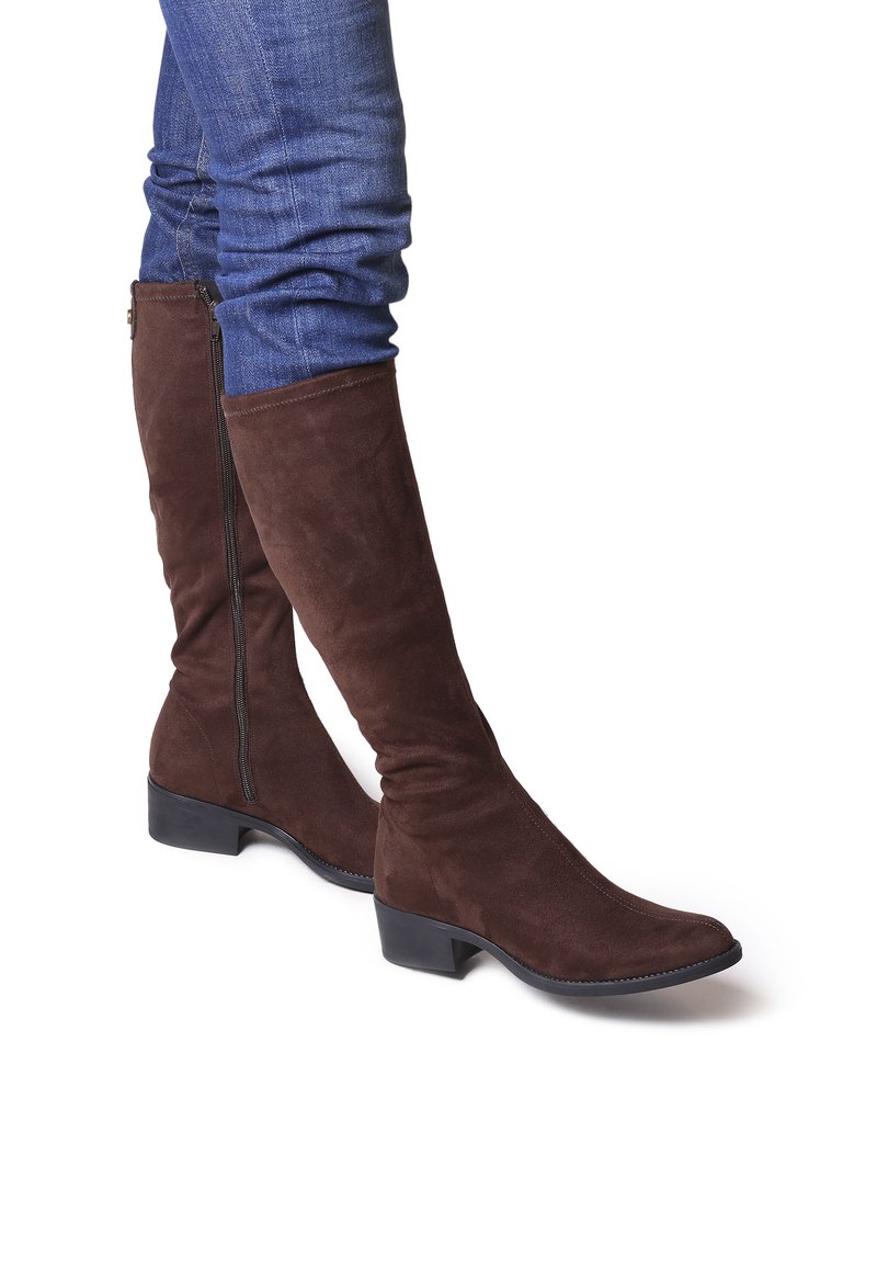 Stivali al ginocchio in suede marrone con un design elegante, caratterizzati da una cerniera laterale e un tacco basso, abbinati a jeans aderenti blu.