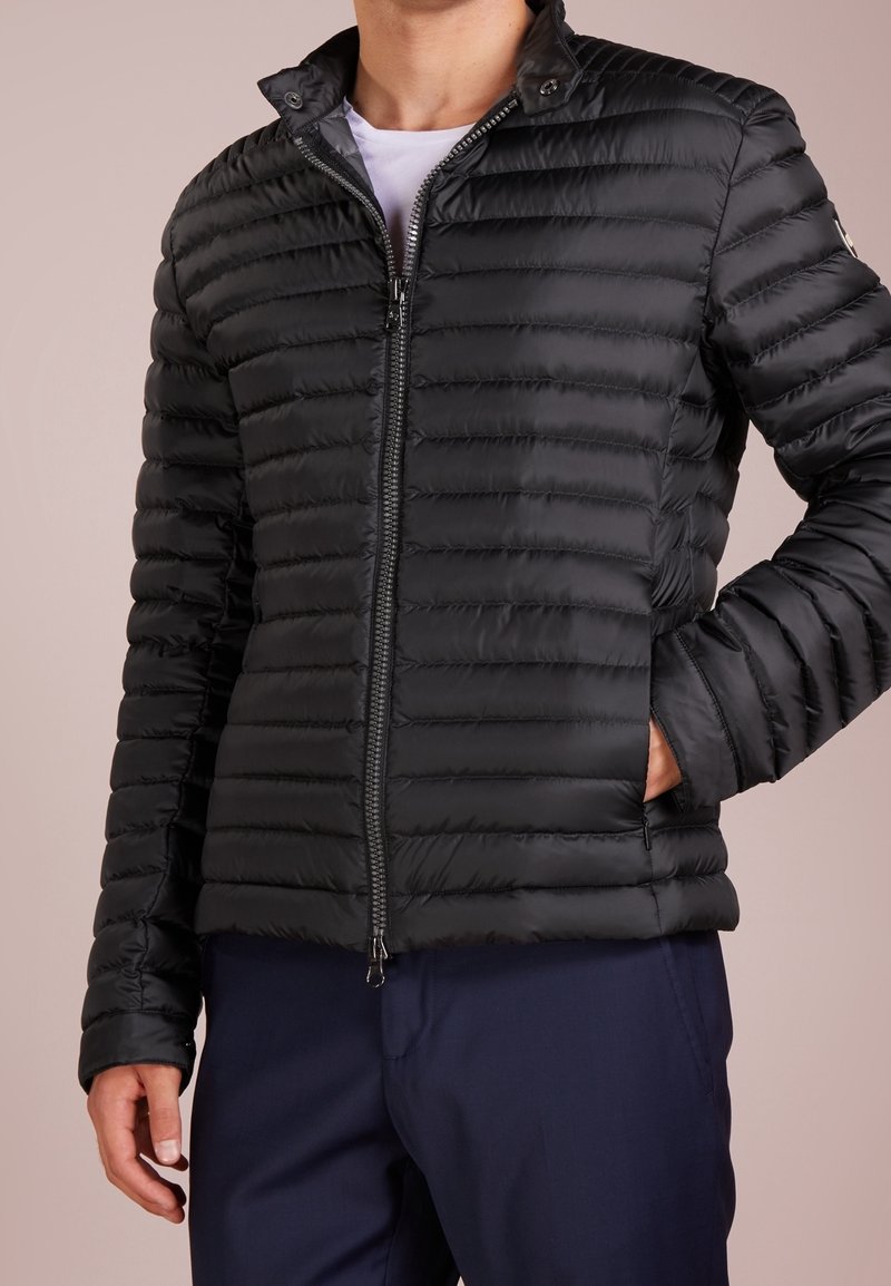 Svart vadderad jacka med dragkedja, featuring en ståkrage och horisontell quiltad yta. Slim fit med sidofickor.