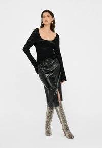 Black long-sleeve top with textured knit pattern, paired with a shiny black leather pencil skirt featuring a side slit, and knee-high snake print boots.