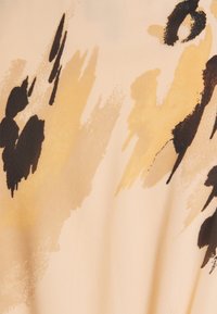 Tela ligera con un fondo beige y manchas abstractas en marrón y amarillo mostaza. Textura suave con elementos de diseño fluidos.