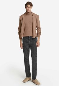 Beige polotröja, lager med matchande sjal, ihopparad med mörkgrå raka jeans och ljusbeige skor. Enkel design, mjuk textur.