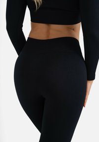 Black ribbed leggings with a high waistband, featuring a smooth texture and a fitted design that contours to the body.