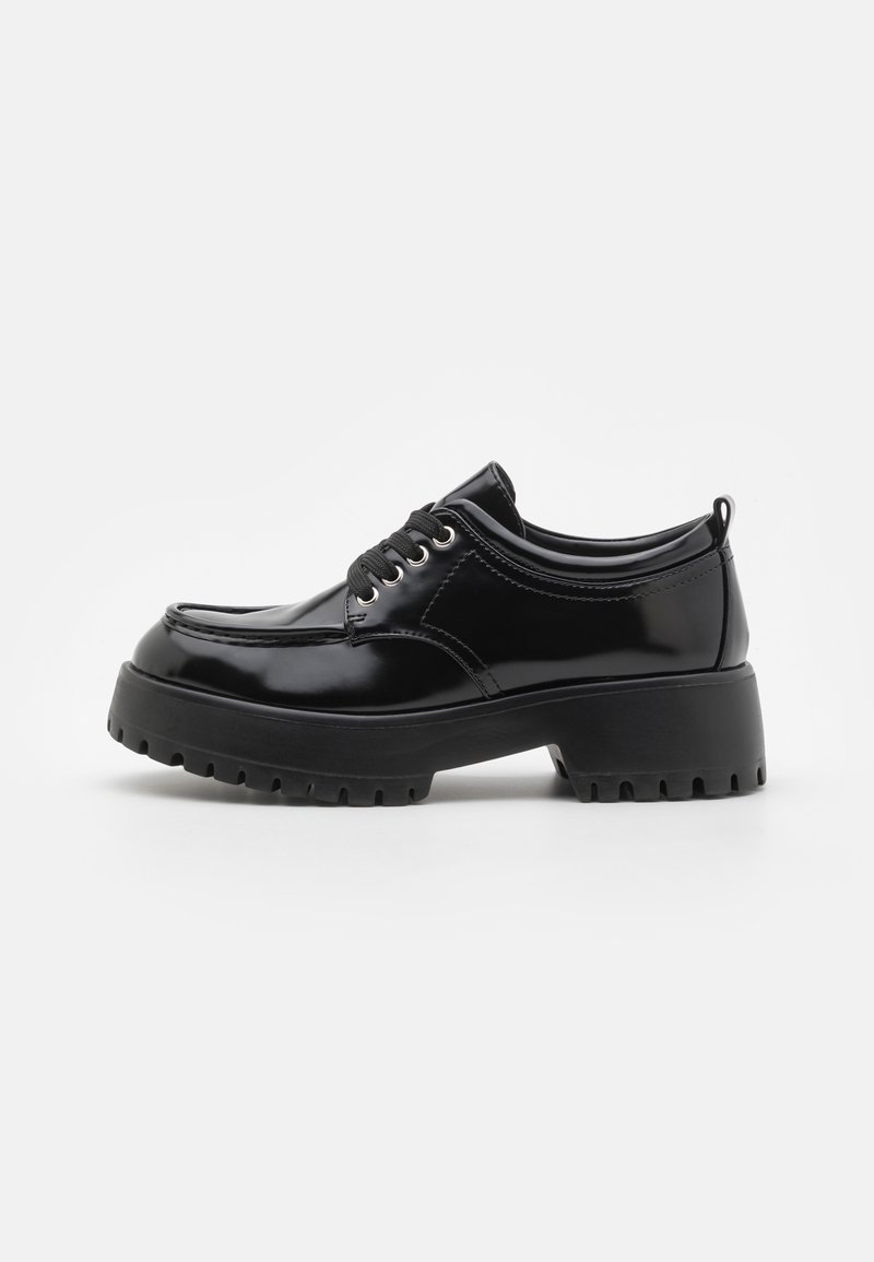 Chaussure à lacets en cuir noir brillant avec une semelle épaisse à crampons et un bout arrondi, conçue pour un usage décontracté ou formel.