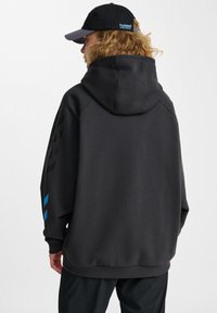 Huvtröja i mörkgrå bomullsmix, med en stor baksida, ribbade ärmslut och blå detaljer på vänster ärm.