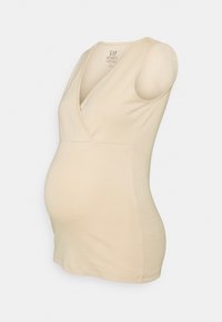 Top de maternidade bege, com decote em V, sem mangas e tecido elástico para conforto, adequado para acomodar uma barriga em crescimento.