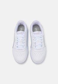 Chaussures de sport blanches en cuir synthétique, avec une surface lisse, un bout rond, un système de laçage et une semelle texturée avec des perforations.