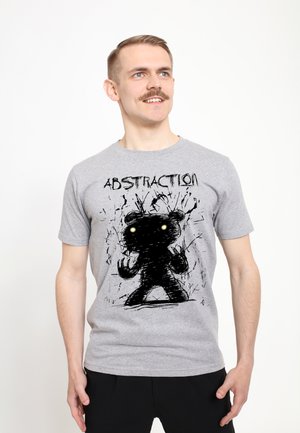 Mand med overskæg iført en grå t-shirt med et sort abstrakt bjørnemotiv og ordet "ABSTRACTION" på brystet.