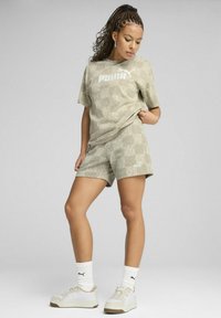 Lichtgroene, gestructureerde sportoutfit bestaande uit een T-shirt met korte mouwen en shorts, beide met een wit Puma-logo. Gecombineerd met witte sneakers.