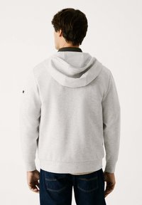 Sudadera con capucha de color gris claro, con un corte relajado, puños y dobladillo acanalados, que presenta una textura suave y un logotipo discreto en la manga.