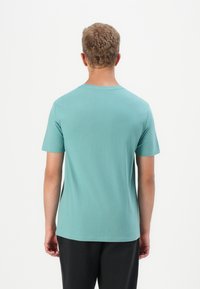 Tricou cu mânecă scurtă, de culoare teal deschis, fabricat din bumbac moale, cu gât rotund clasic și o croială lejeră, cu tivuri cosute.