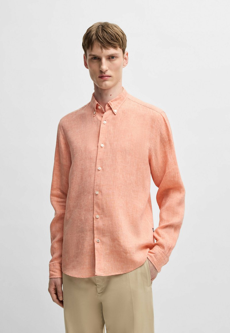 Camicia button-up in lino di un leggero corallo, con colletto classico, maniche lunghe e orlo curvo. Caratterizzata da bottoni bianchi e una trama sottile.