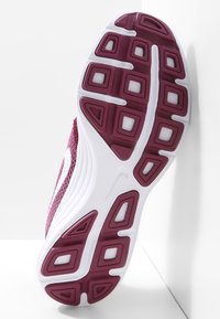 Semelle de chaussure de sport avec semelle en caoutchouc bordeaux et intermédiaire blanche, inclinée contre un fond blanc montrant le motif de grip détaillé.