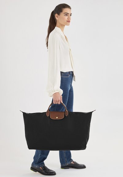 Schwarze Nylon-Tasche mit braunen Lederakzenten und einem Obergriff. Sie verfügt über einen Reißverschluss und ein geräumiges Innendesign.