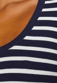 Marinblå och vit randig tyg med en ribbad textur. Har en rundad halsringning och en slät, sömlös yta.