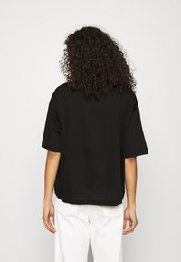 Černé oversized tričko s krátkým rukávem, vyrobené z měkké bavlny. Záda mají hladkou texturu s čistým, jednoduchým designem.