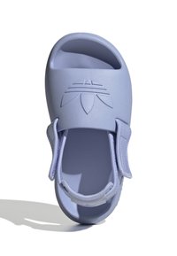 Světlé fialové sandály vyrobené z měkkého materiálu. Mají široký pásek a výřezový design, s texturovaným logem na vrchní části.