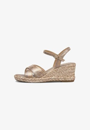 Sandale compensée avec plateforme en jute tressé, brides croisées métalliques et fermeture à boucle à la cheville dans des tons beige et or sur fond blanc.