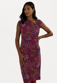Vestido ajustado com mangas em forma de boca de jacaré na cor rosa, com padrões intrincados de paisley em roxo, laranja e azul-marinho. Apresenta um detalhe em nó e um lado franzido.