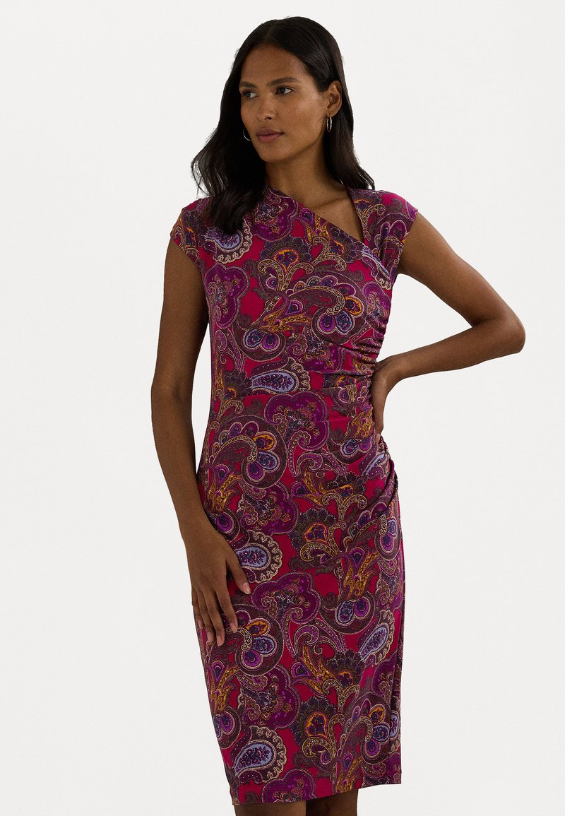 Vestido ajustado com mangas em forma de boca de jacaré na cor rosa, com padrões intrincados de paisley em roxo, laranja e azul-marinho. Apresenta um detalhe em nó e um lado franzido.