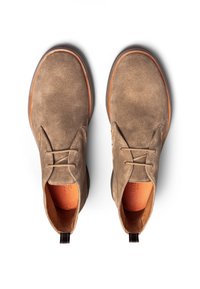 Chaussures en suede marron à lacets avec un nez rond, un intérieur orange contrastant, une surface texturée et des semelles en caoutchouc marron. Elles disposent de languettes arrière.
