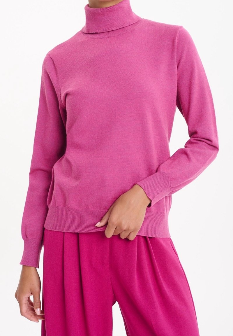 Figursydd rosa polotröja med långa ärmar, ribbade muddar och nederkant. Mjuk textur med en slät yta. Kombinerad med matchande rosa byxor.