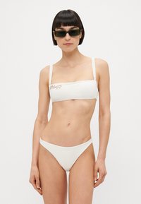 Balta bikini ar bandeau topu un regulējamiem siksniņām. Iekļauj ziedu izšuvumu uz topa. Gluda auduma un klasiskā piegriezuma.